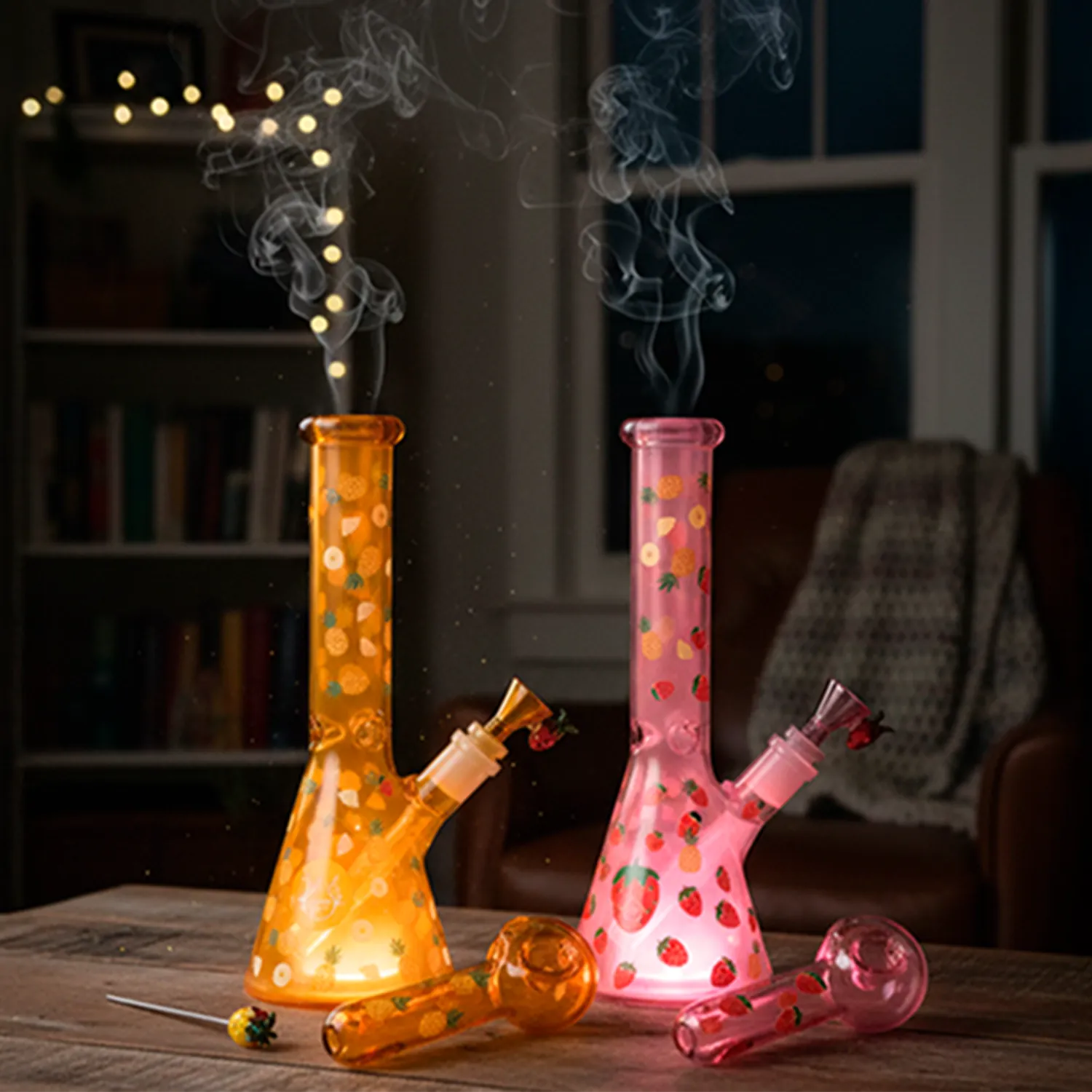 Two upright 8" Pulsar Fruit Series Pineapple Express Glow In The Dark Dab Rig Kit - 8" / 14Mm F pieces, orange and pink, lit from below on a wooden table with smoke rising.
