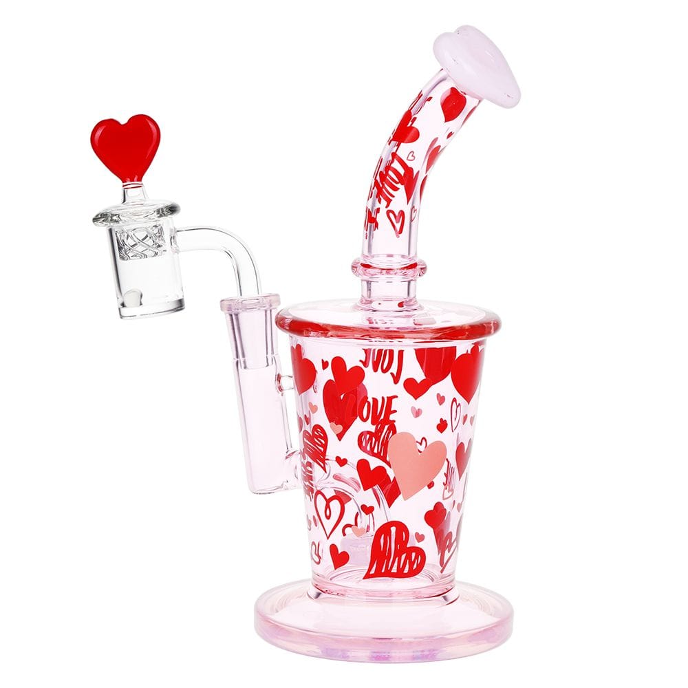 Angled studio shot of the Pulsar Valentine'S Love Hearts Glass Dab Rig Set - 8.5" / 14Mm F showing its pink-tinted glass body and red heart pattern with a heart-topped banger.
