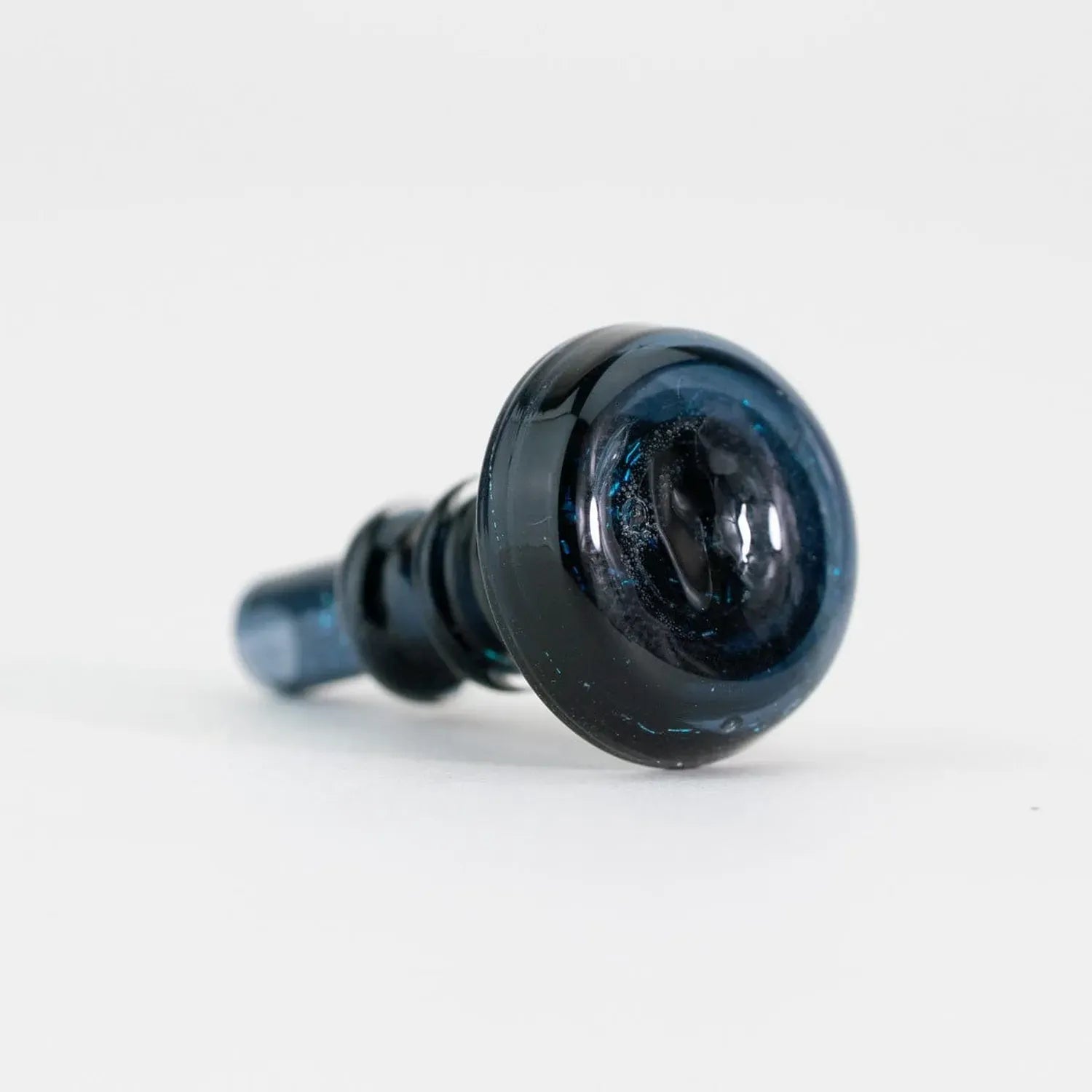 Close-up, low-angle view of the black glass Empire Glassworks PuffCo Peak Pro 3D XL Chamber Glass Joystick Cap - Black Nebula showing its rounded top and subtle blue flecks.