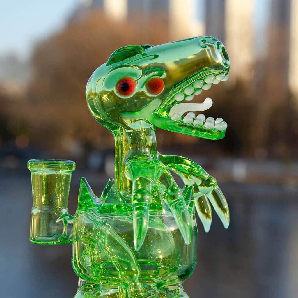 A close-up, angled view of the FAB DINO, a green glass sculpture with a textured, ridged design.