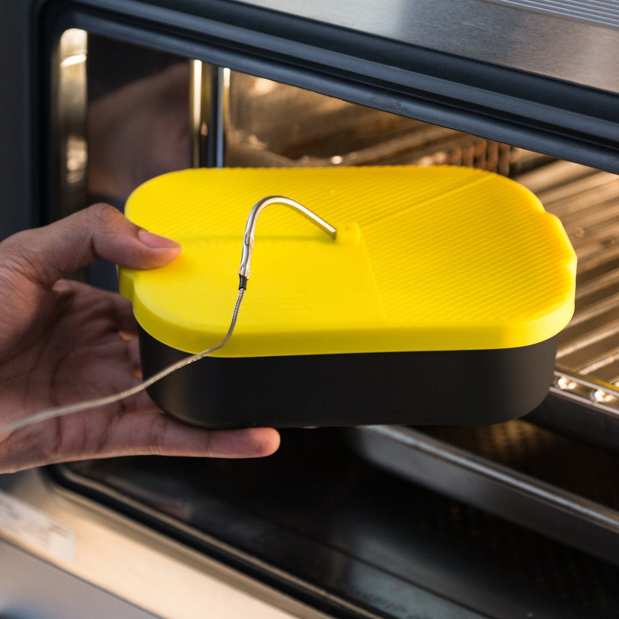 A hand holds the Decarb9 Herbal Decarboxylator Kit inside an oven, showcasing its compact size and metallic interior reflection.