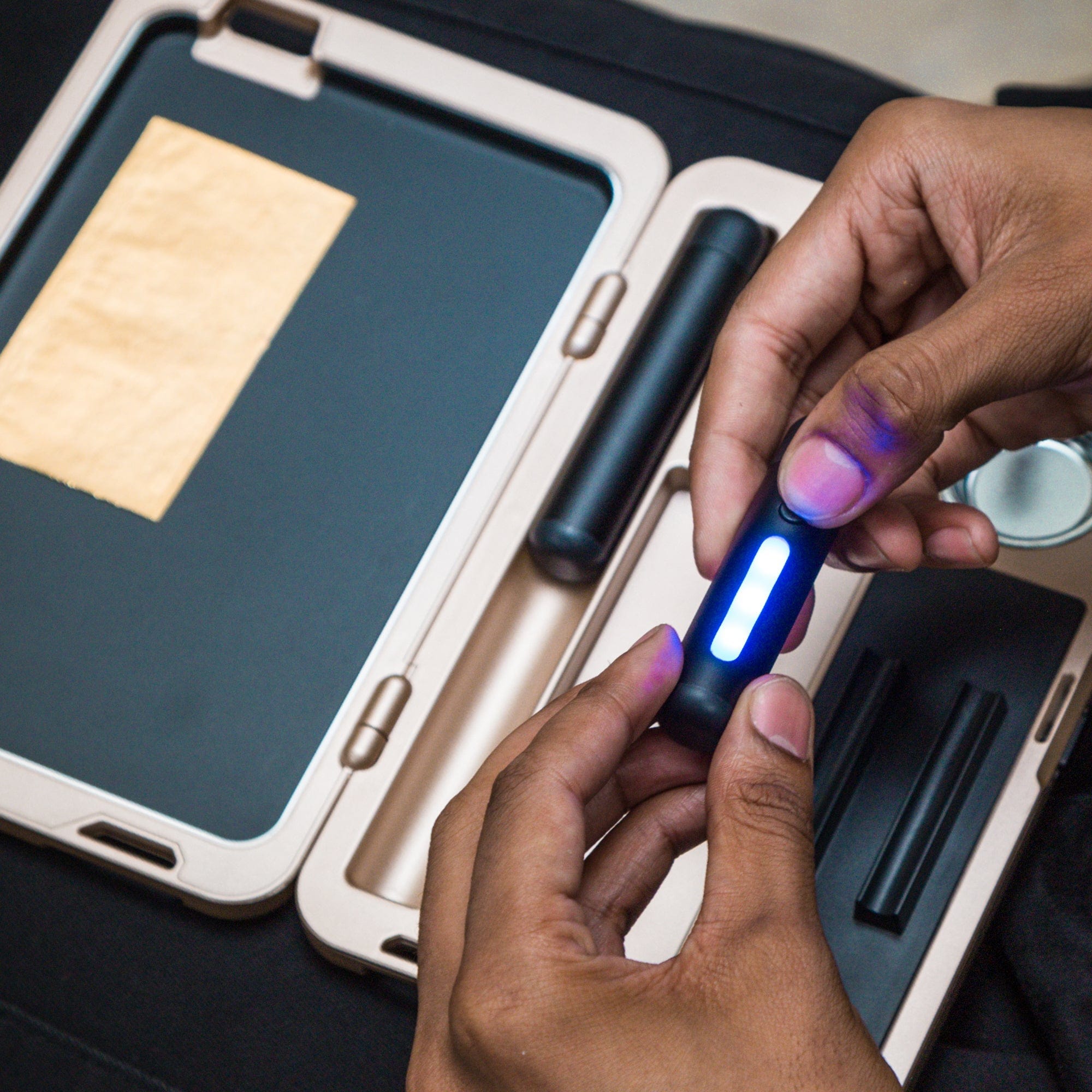 A close-up, angled view shows hands opening the M.L.T.9 Portable Rolling Tray Survival Kit, revealing its contents on a dark background.