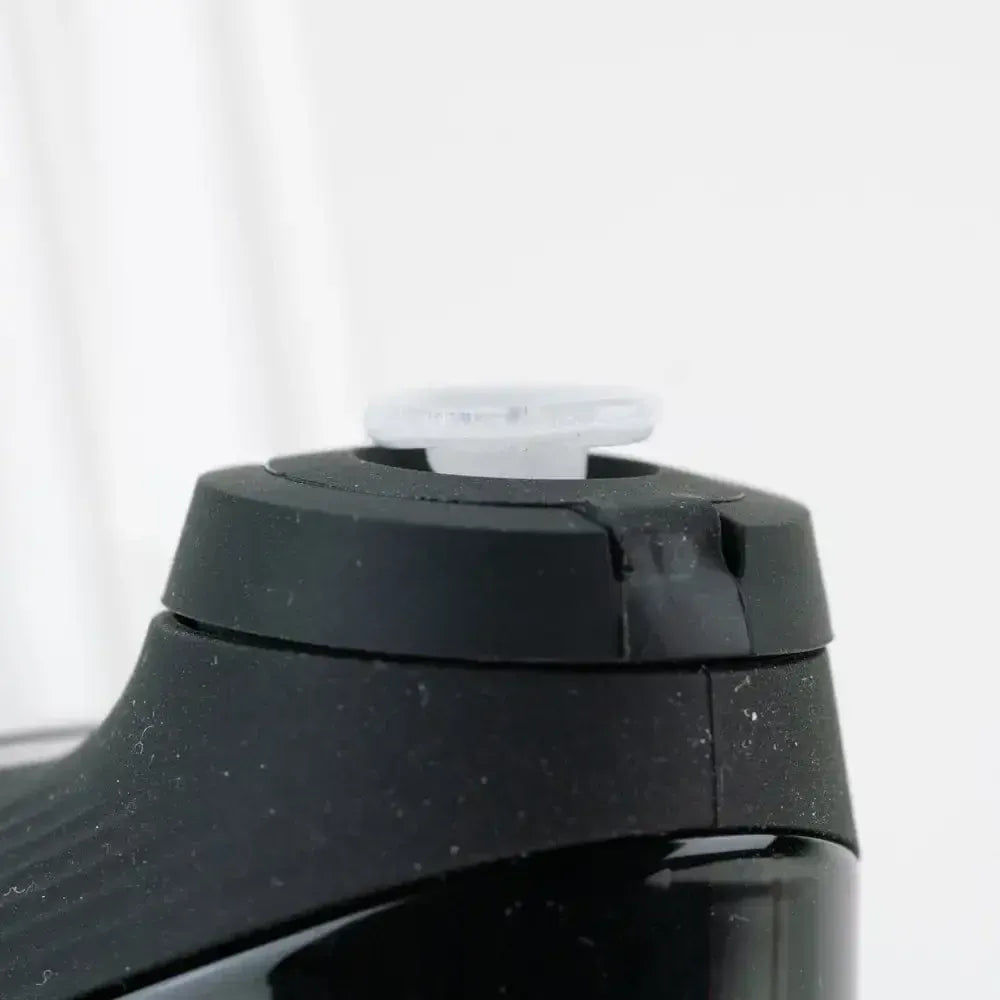 Close-up angled view of the Empire Glassworks PuffCo 'New Peak' & Proxy Glass Joystick Cap - Glow in the Dark perched on a black device against a soft white background.