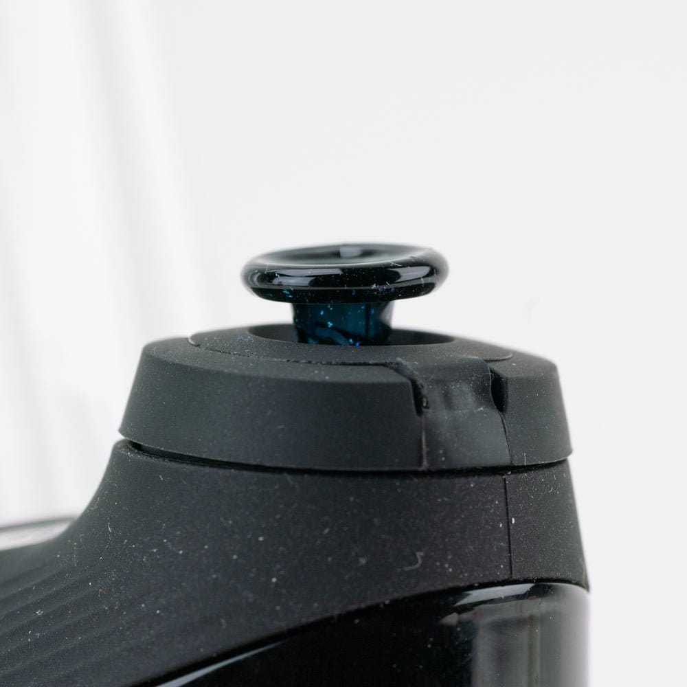 Close-up of the Empire Glassworks PuffCo 'New Peak' & Proxy Glass Joystick Cap - Nebula Black mounted on a matte black device, shown from a slight side angle against a soft white background.
