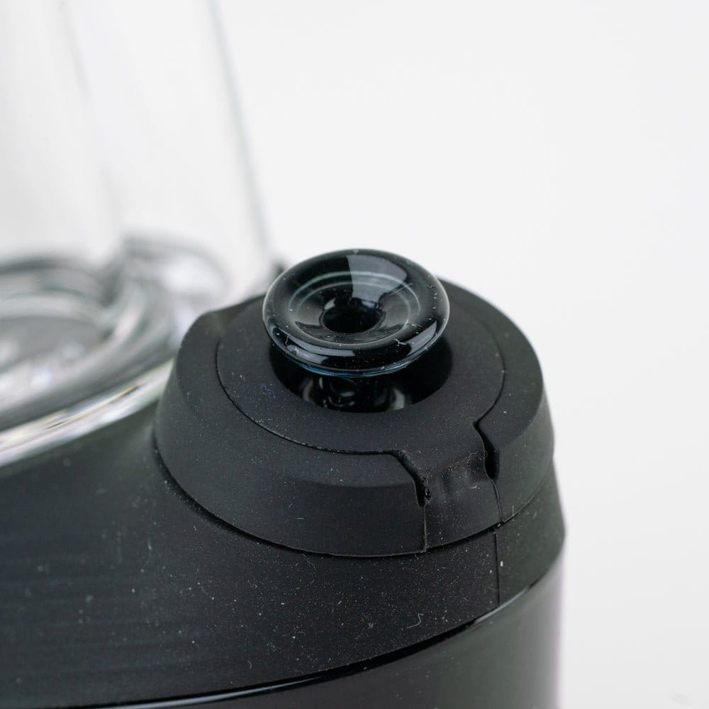 Close-up angled view of the Empire Glassworks PuffCo 'New Peak' & Proxy Glass Joystick Cap - Nebula Black sitting atop a black device, showing the glossy black glass joystick cap and matte black silicone collar.