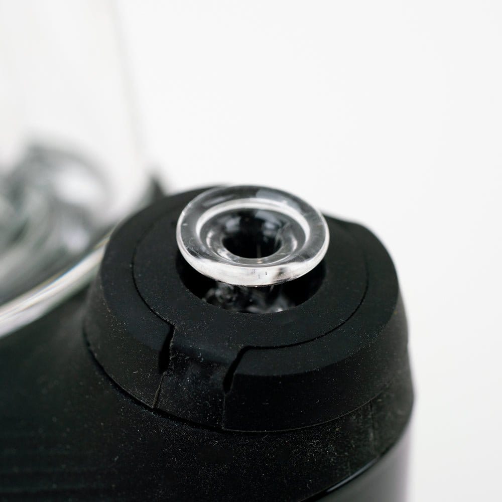 Close-up top view of the Empire Glassworks PuffCo 'New Peak' & Proxy Glass Joystick Cap - Pink UV showing the clear circular glass cap seated in a black rubberized mount.