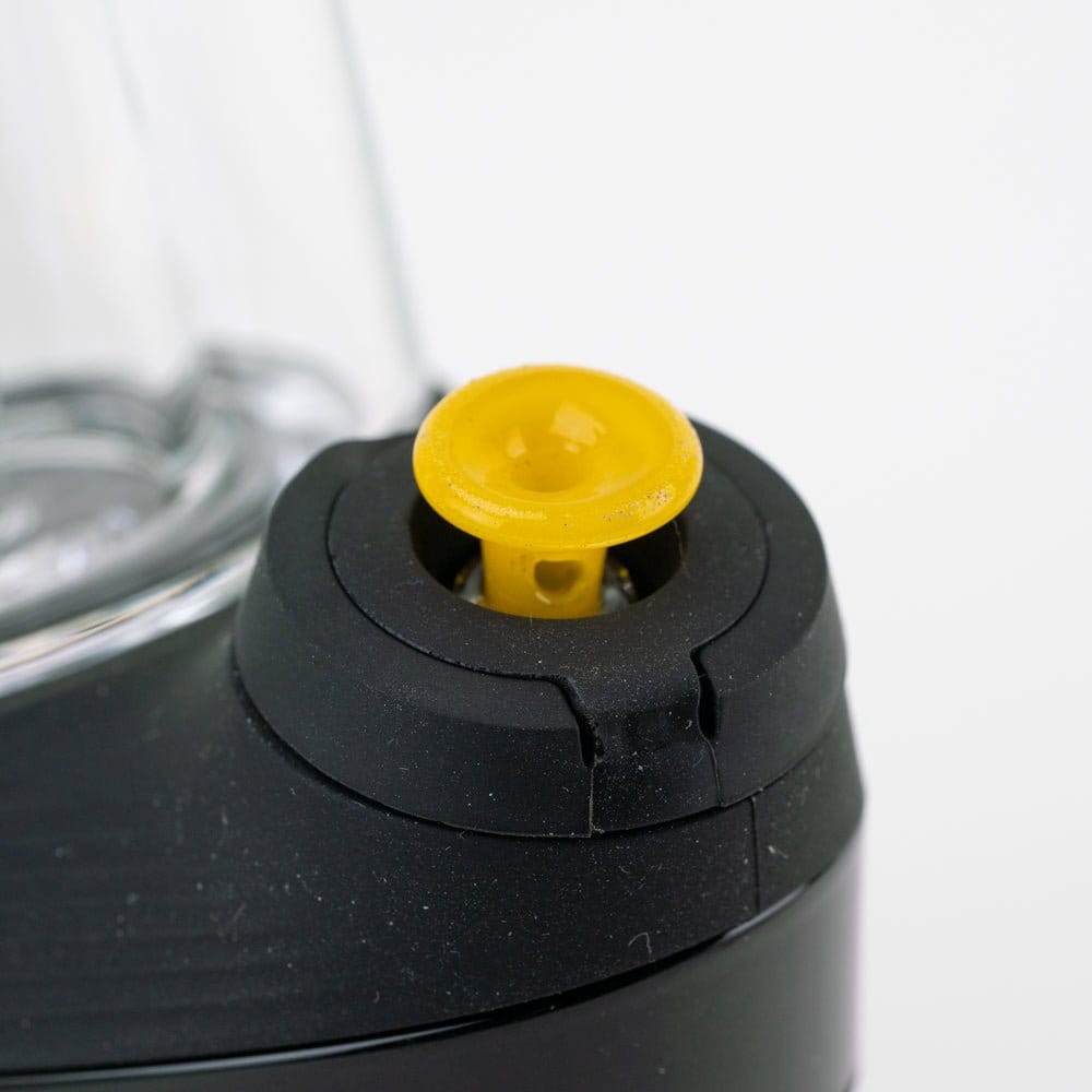 Close-up of the Empire Glassworks PuffCo 'New Peak' & Proxy Glass Joystick Cap - Sunshine Yellow showing a top-down view of the small yellow joystick seated in a black rubber mount.