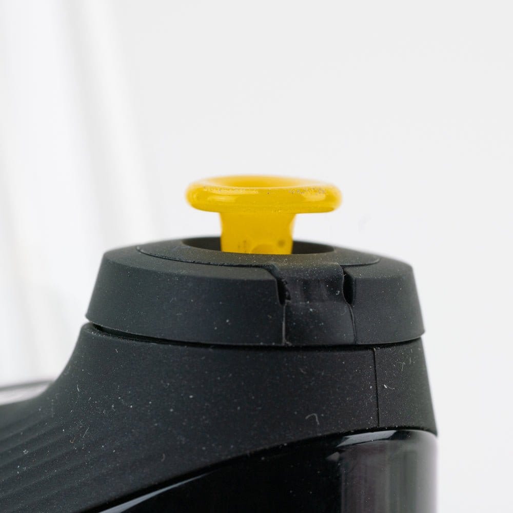 Close-up front view of the Empire Glassworks PuffCo 'New Peak' & Proxy Glass Joystick Cap - Sunshine Yellow seated in a black device, showing the small yellow glass joystick against a soft white background.