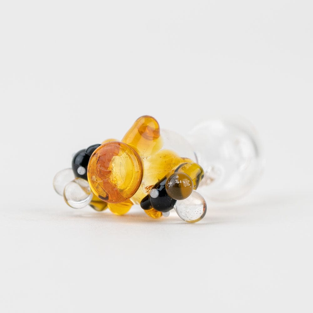 A close-up, angled view of the Beehive PuffCo Peak Pro Glass Ball Cap with translucent amber glass.