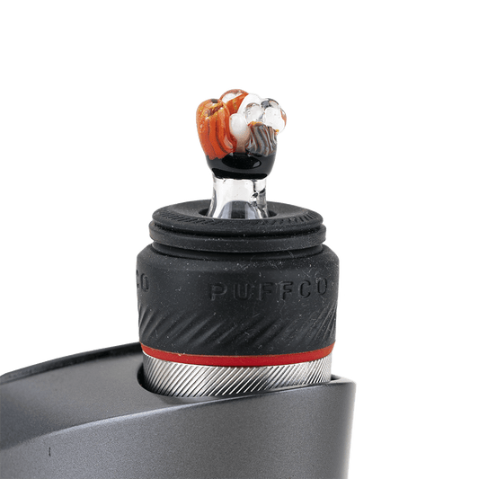 A close-up, angled view of the Coral PuffCo Peak Pro Glass Ball Cap, showing its smooth, rounded form and reflective surface.