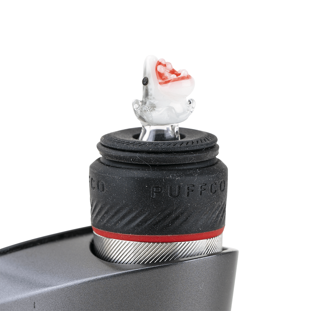 A close-up view of the Jawsome PuffCo Peak Pro Glass Ball Cap resting on a metal connection.
