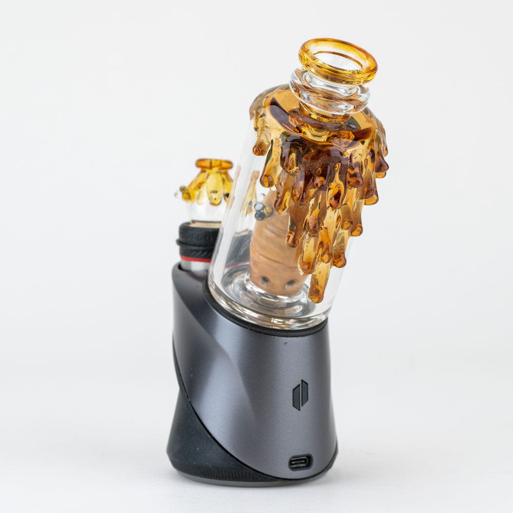 A close-up, angled view of the "Save the Bees" PuffCo Peak & Peak Pro Glass Attachment, showing a honey-toned glass piece.