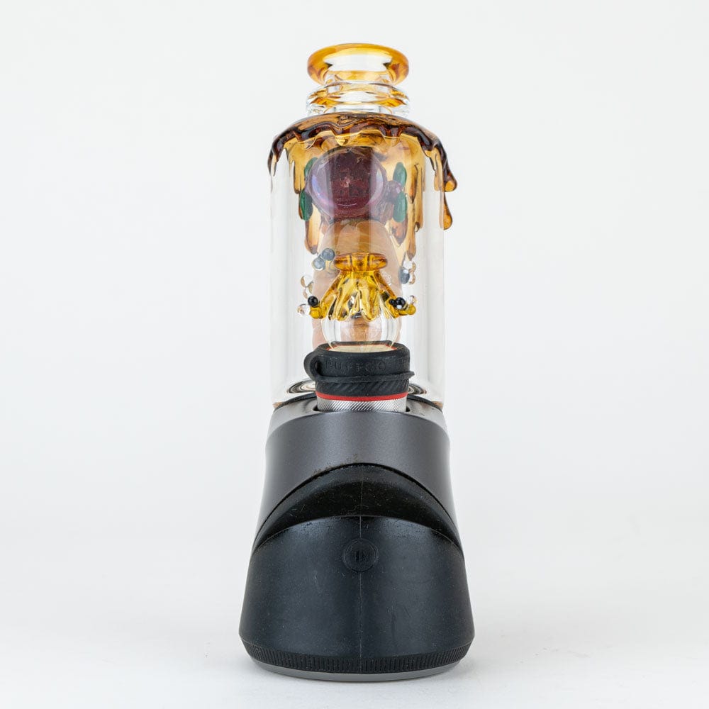 A close-up, angled view of the “Save the Bees” PuffCo Peak & Peak Pro Glass Attachment, showcasing its amber-toned, detailed bee design.