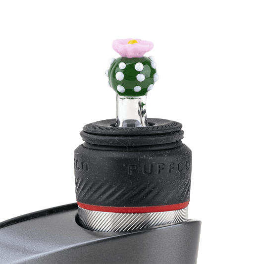 Close-up of the Peyote PuffCo Peak Pro Glass Ball Cap, showcasing its textured surface and rounded form against a dark backdrop.