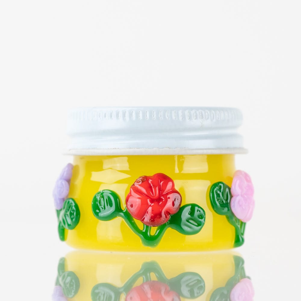 A close-up of the Sunshine Garden Terp Jar, showing its colorful, patterned glass container from a slightly angled perspective.