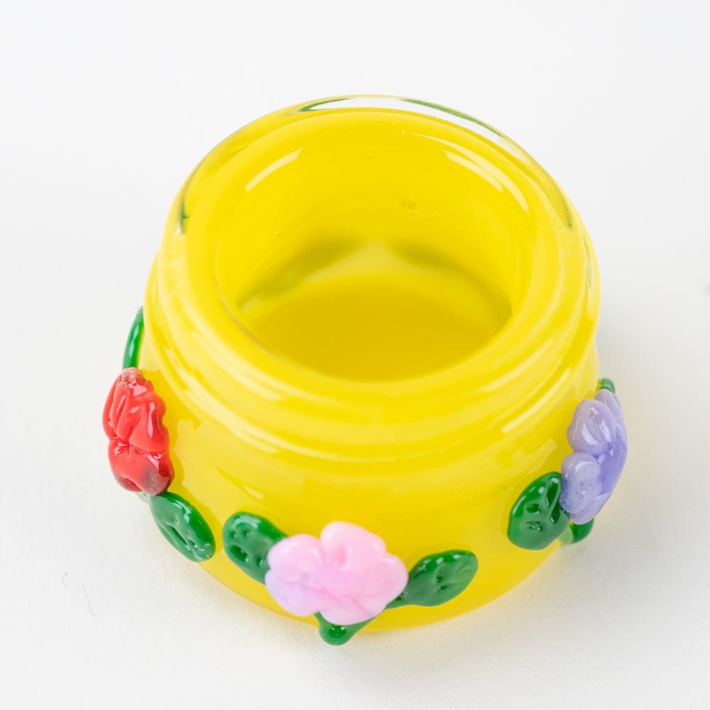 A slightly angled view of the Sunshine Garden Terp Jar, showcasing sculpted floral details on a colorful glass container.