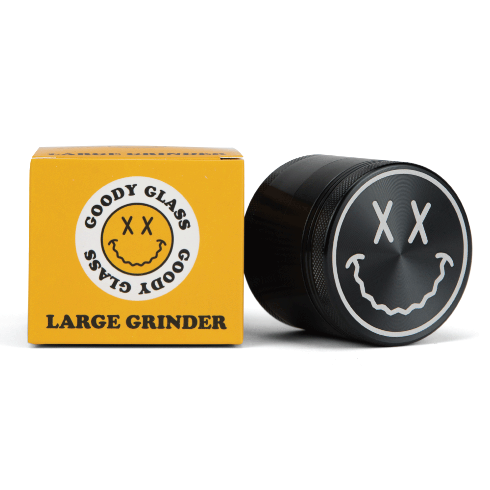 A close-up shot of the Goody Big Face Travel Size Grinder, featuring a dark-colored, circular design with a facial graphic.
