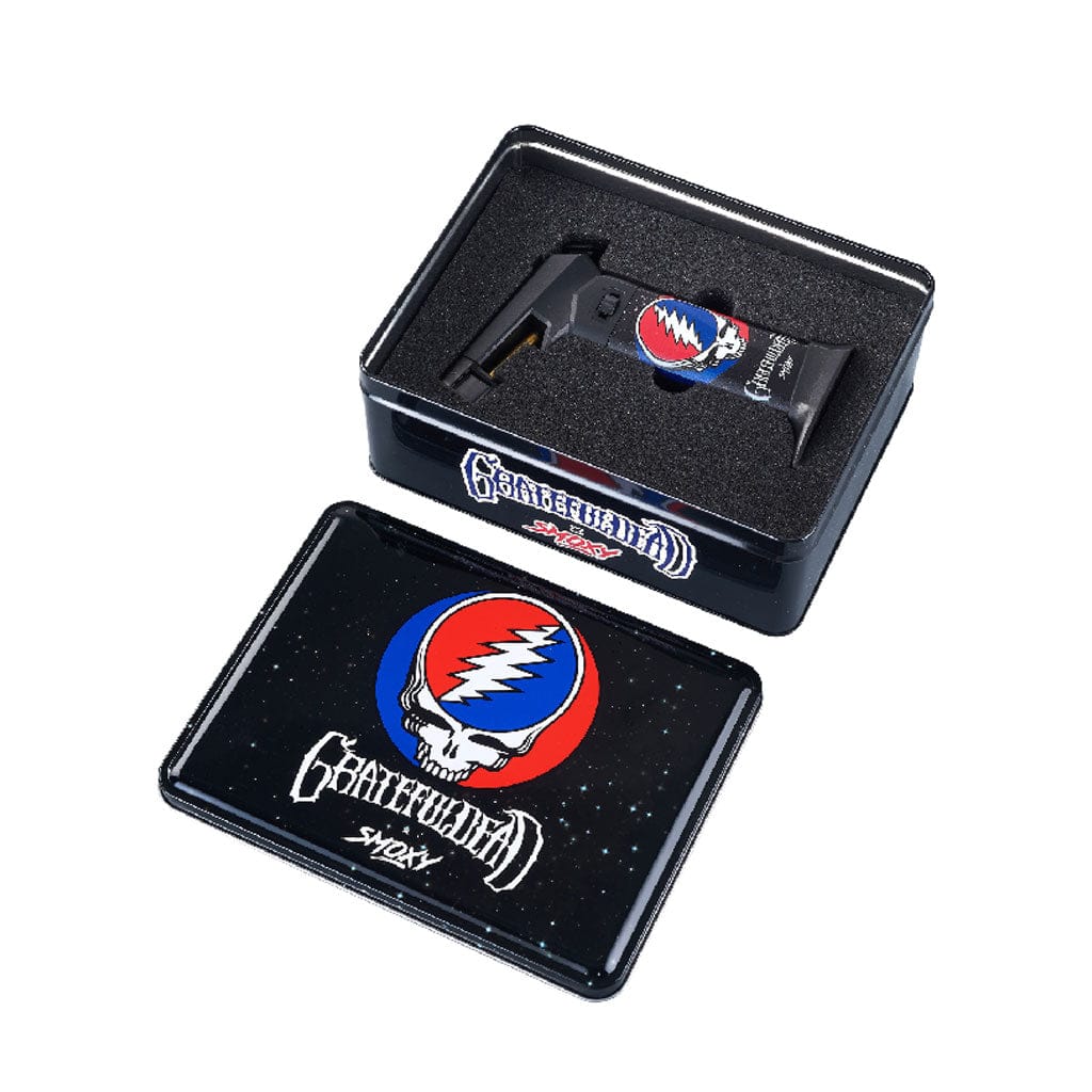 Angled top view of the Grateful Dead The Rock Torch in a black foam-lined tin, its red‑and‑blue skull logo visible on the torch and lid.