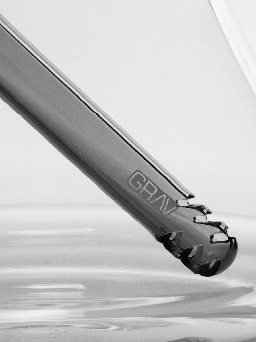 A close-up, angled view of the Large Accented Deco Beaker Bong, showcasing its smooth glass form against a dark background.