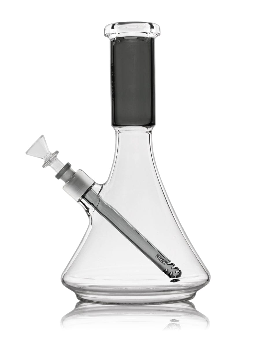 A studio shot displays the Large Accented Deco Beaker Bong, with a clear glass body and a simple, elegant design reflected on a glossy surface.