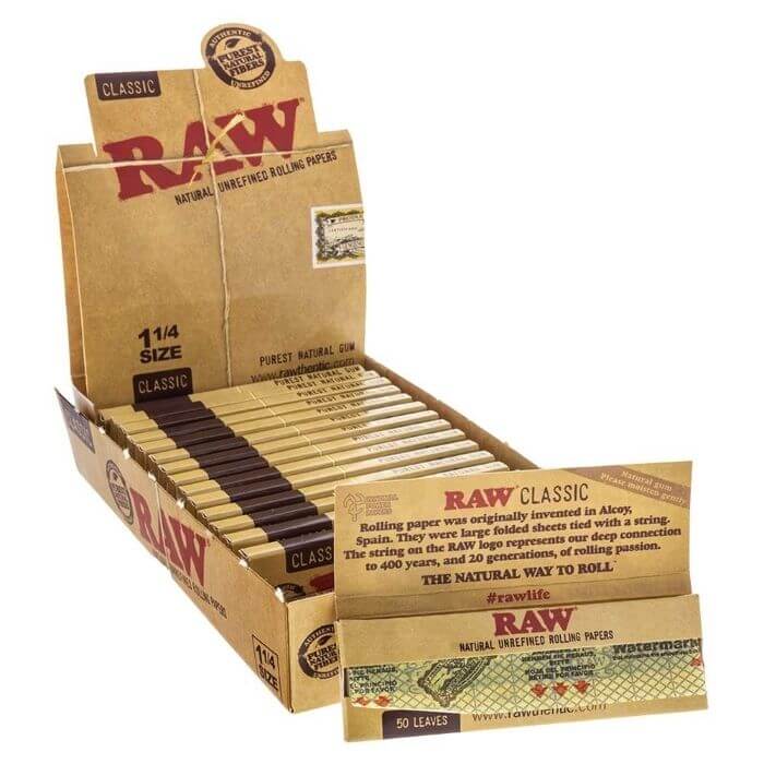 Close-up of RAW Classic 1 1/4 Rolling Papers packaging, featuring a bold logo and size details on a textured surface.