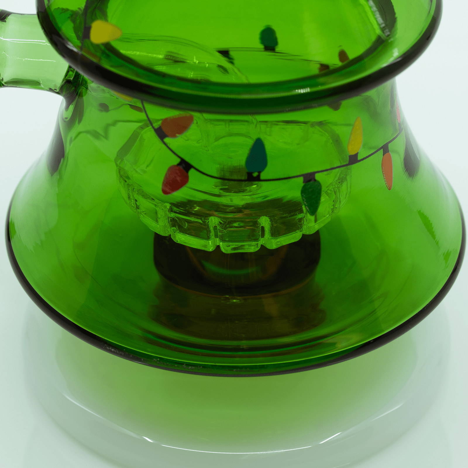 Close-up top-down view of the green glass Christmas Tree XL Bong showing painted multicolored string lights around the bell-shaped base.