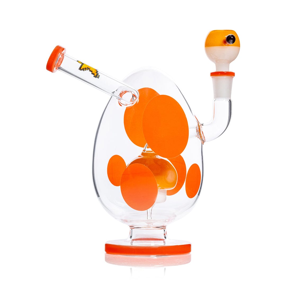 Angled studio shot of the Hemper Spotted Egg XL Bong showing its egg-shaped clear glass body with bright orange spots, matching orange accents, and a side-mounted downstem.