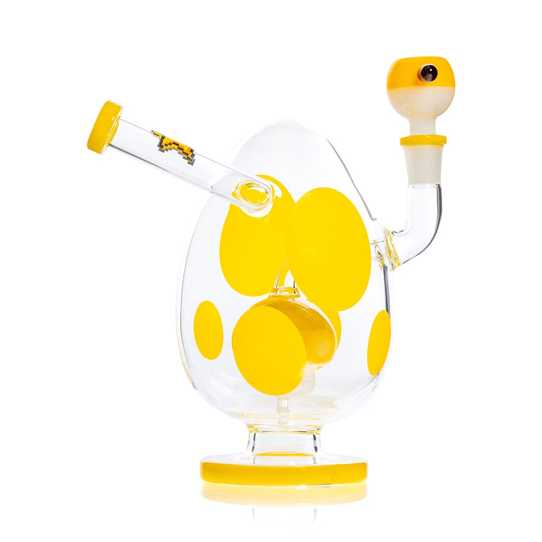 Angled front view of the Hemper Spotted Egg XL Bong showing a clear egg-shaped body with large yellow polka dots, matching yellow accents, and a side mouthpiece against a white background