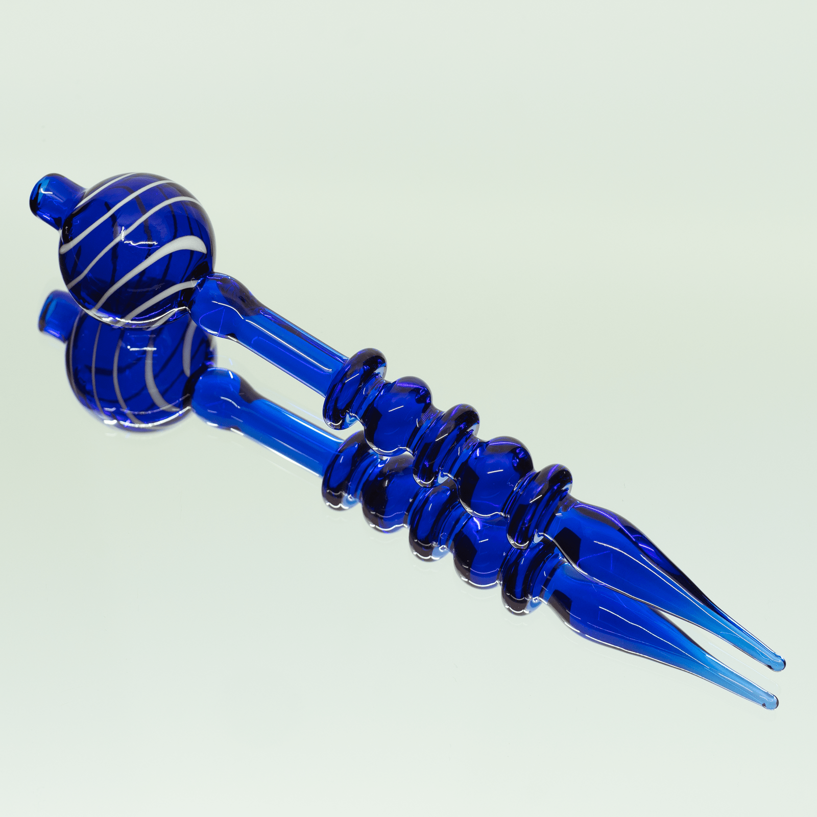A close-up shot of the Bubble Head Dab Tool & Carb Cap, featuring a blue glass head and angled tip against a plain background.