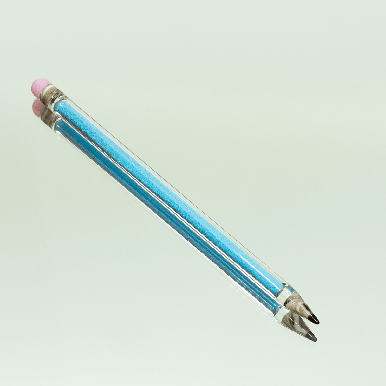 A close-up of the Glitter Pencil Dab Tool against a pale green background, showing its slender design.