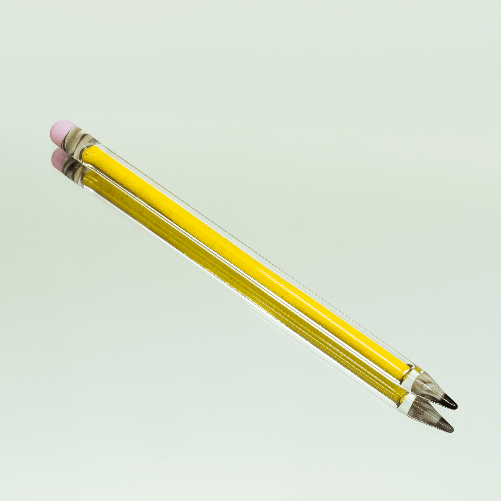 A close-up view of the Glitter Pencil Dab Tool, with a slender, clear glass tip angled against a plain background.