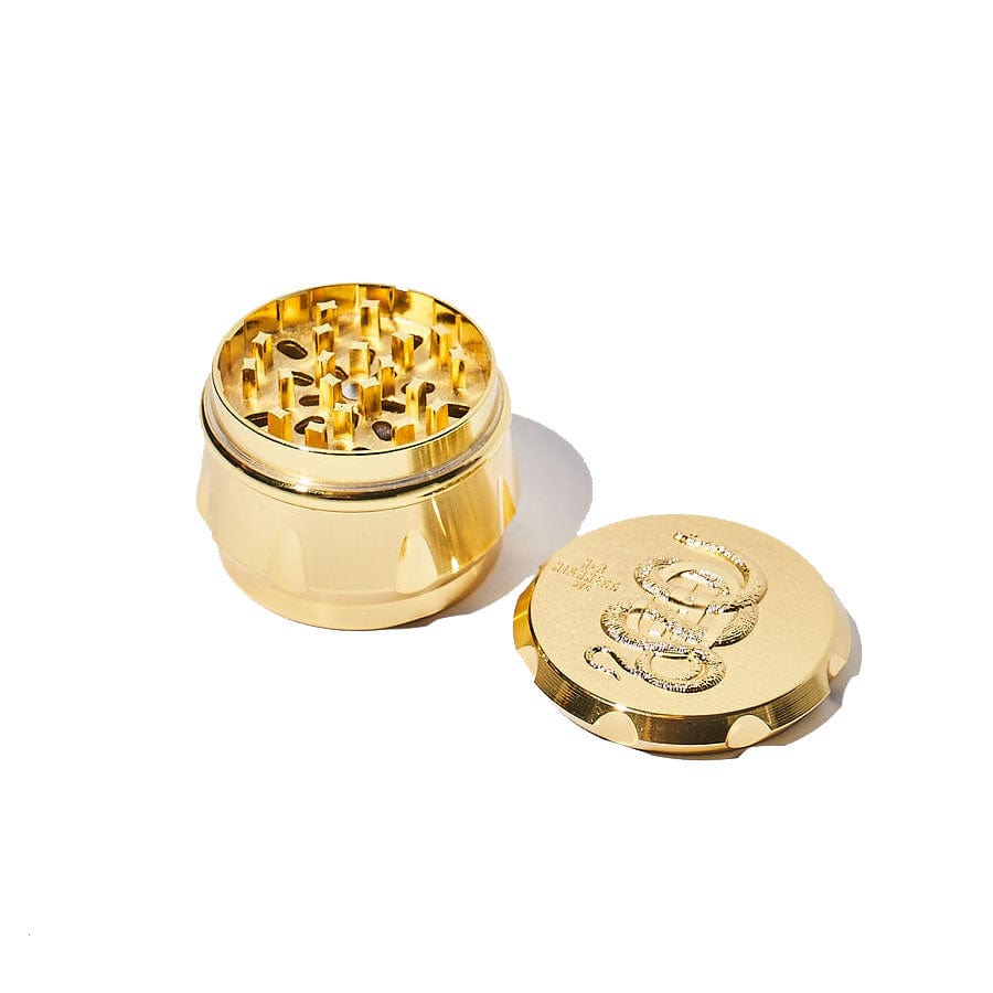 Top-down view of the open Grindzilla Luxury Grinder, revealing metallic grinding teeth within its golden, circular form.