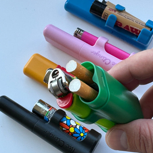 The Clinger Stage 2 Dual Joint Holder rests against a lighter and rolling papers in a close-up shot.
