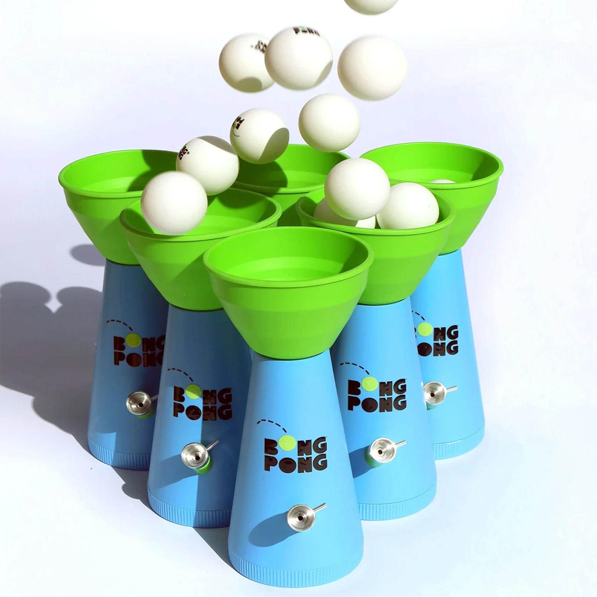 Angled close-up of green cups and blue cones catching white balls midair in the Bong Pong OG setup.