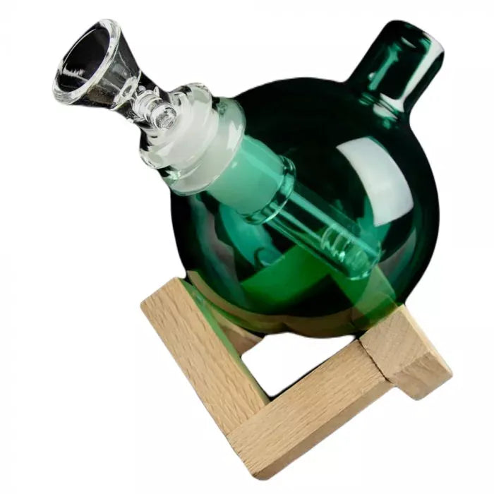 Angled close-up of the green Art of Smoke Orb Bubbler resting in a wooden stand, showing its spherical glass body and clear downstem.
