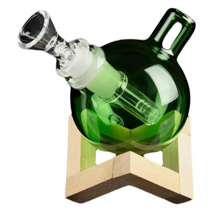 Angled close-up of the green Art of Smoke Orb Bubbler resting on a wooden stand, showing its round body and clear glass mouthpiece