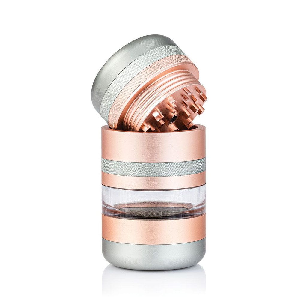 Angled close-up of the rose-gold and silver Ryot Gr8Tr Jar Body Grinder with its top unscrewed to reveal sharp internal teeth and a clear middle chamber