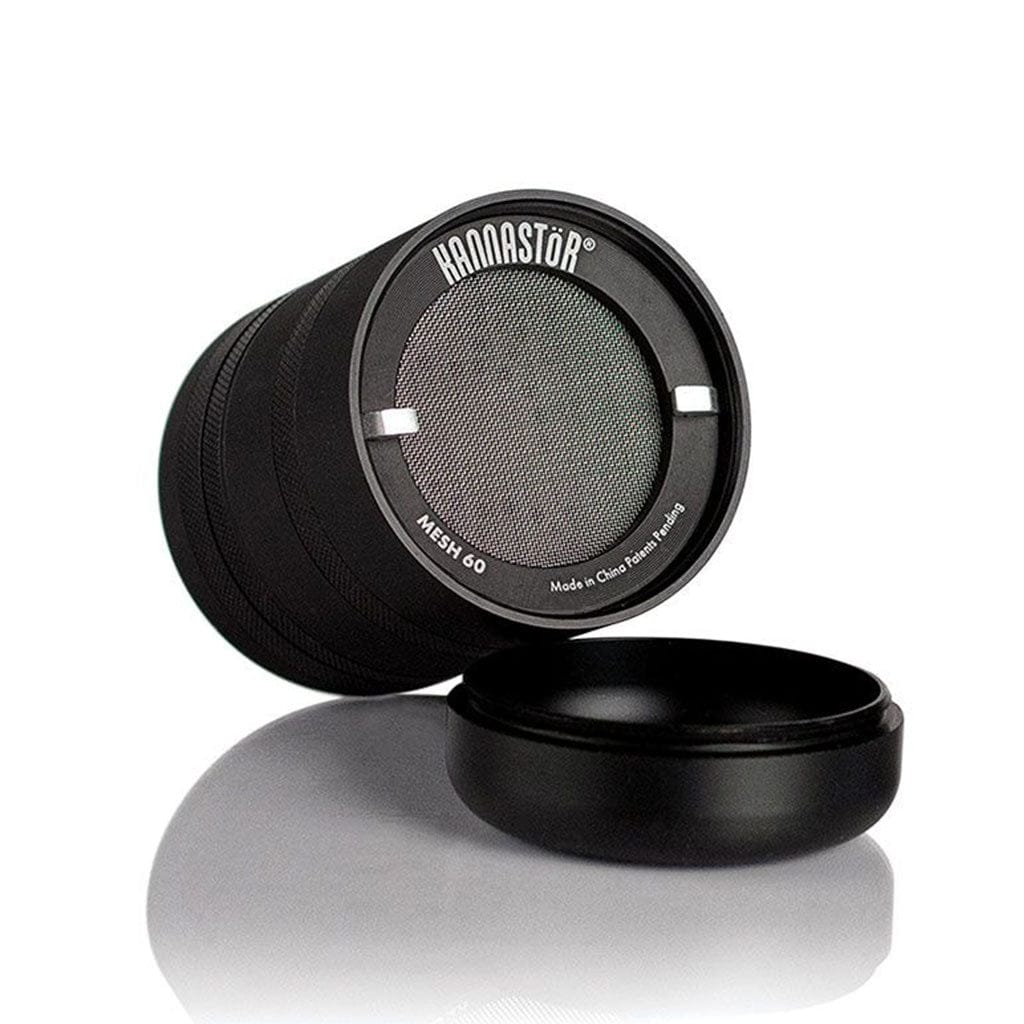 Angled close-up of the black Ryot Gr8Tr Jar Body Grinder showing its mesh screen end and a detached round lid on a reflective white surface