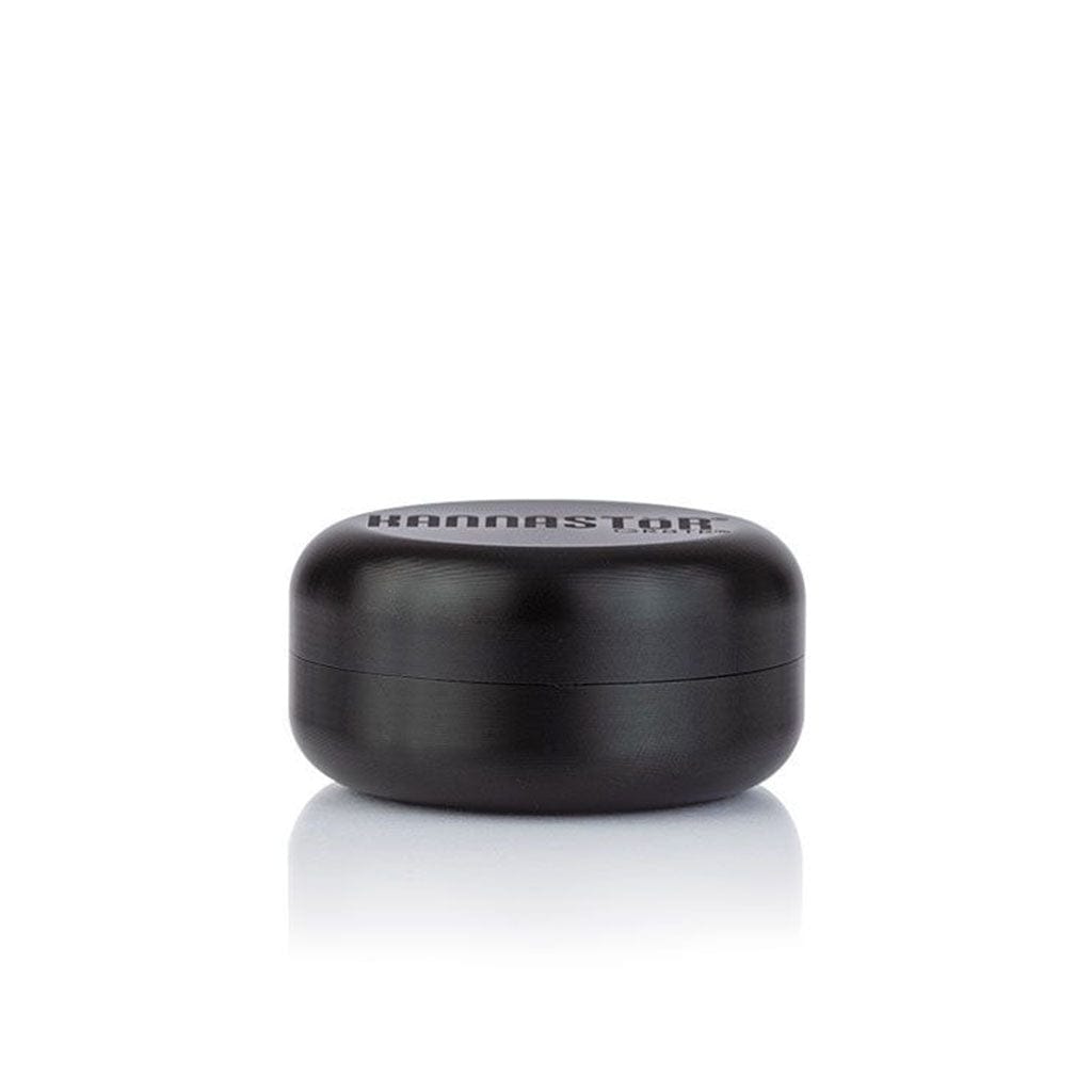 Front-facing view of a matte black Ryot Gr8Tr Jar Body Grinder resting on a reflective white surface, shot with soft, even lighting.