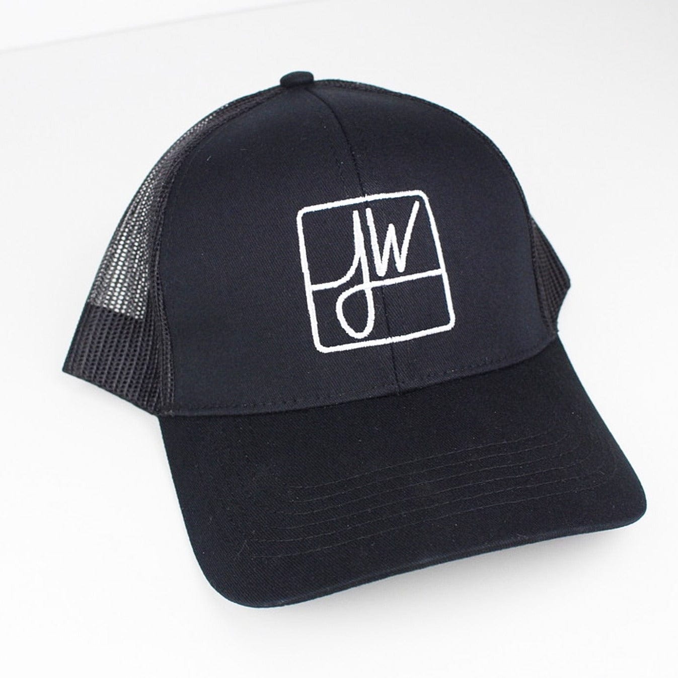 Angled top-down view of a black Jane West Hat trucker cap with white stitched JW logo on the front panel.