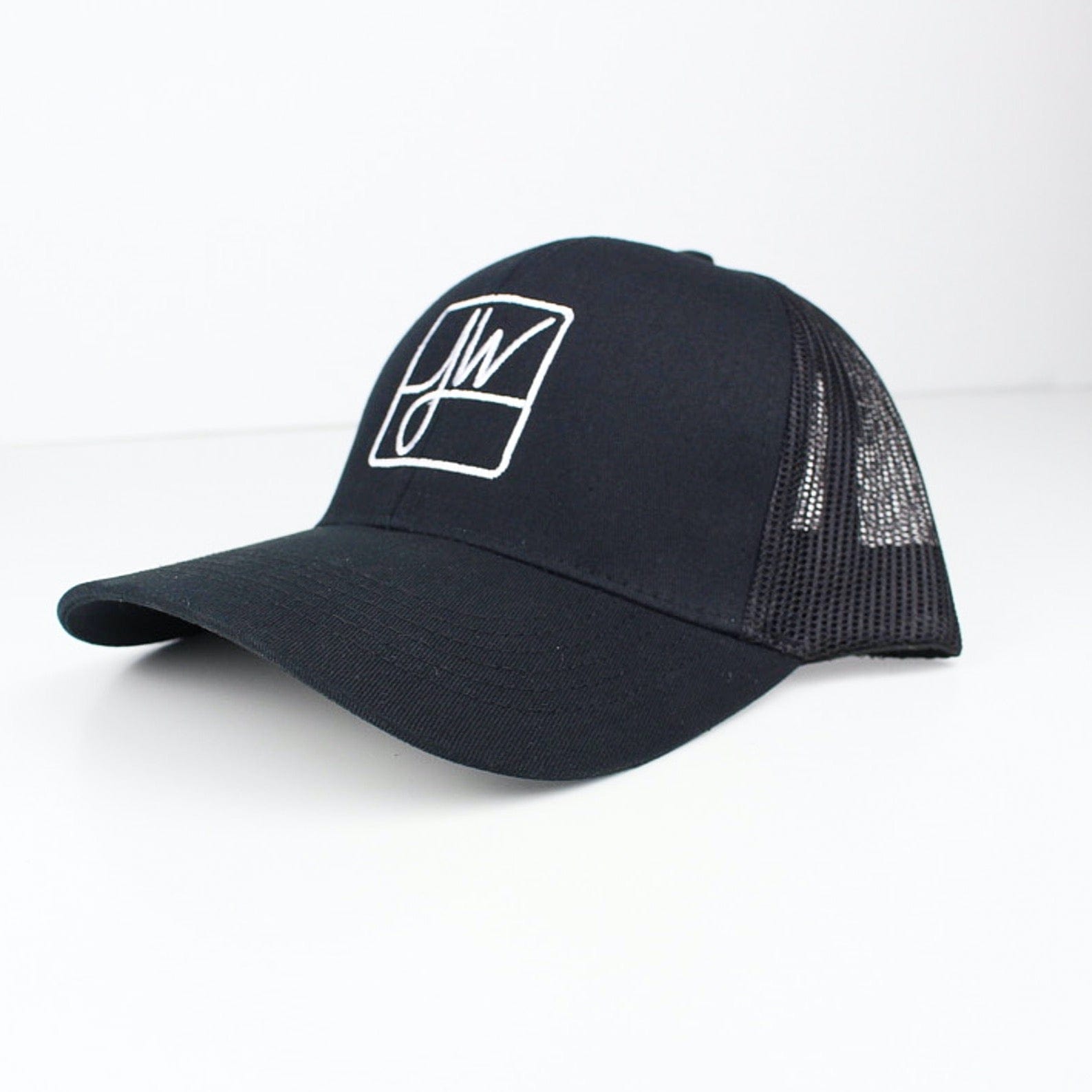 Three-quarter view of a black Jane West Hat trucker cap with white embroidered "JW" logo on the front panel against a white background