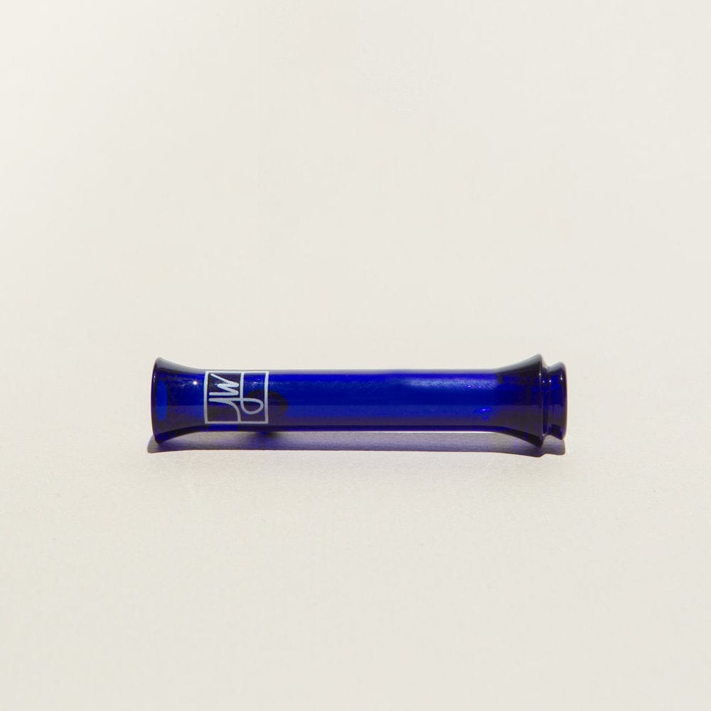 Horizontal studio shot of The Taster // Cobalt, a short cobalt blue glass tube with flared ends and a white logo, on a pale background.