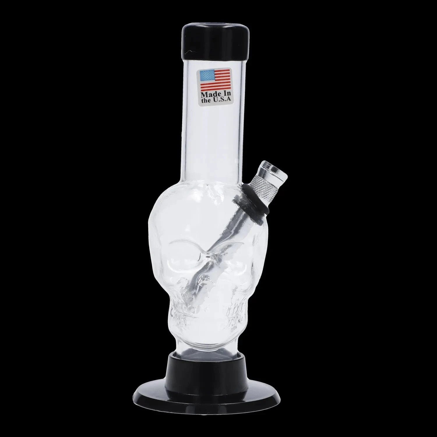 Angled close-up of the JM Plastics Mini Skull Base Acrylic Bong - 6 in. showing a clear skull-shaped body, tilted downstem, and black base against a black background
