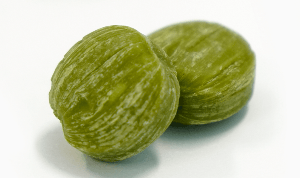 A close-up shows several pieces of Hokkaido Japanese Matcha Milk Candy in a scattered arrangement on a white surface.