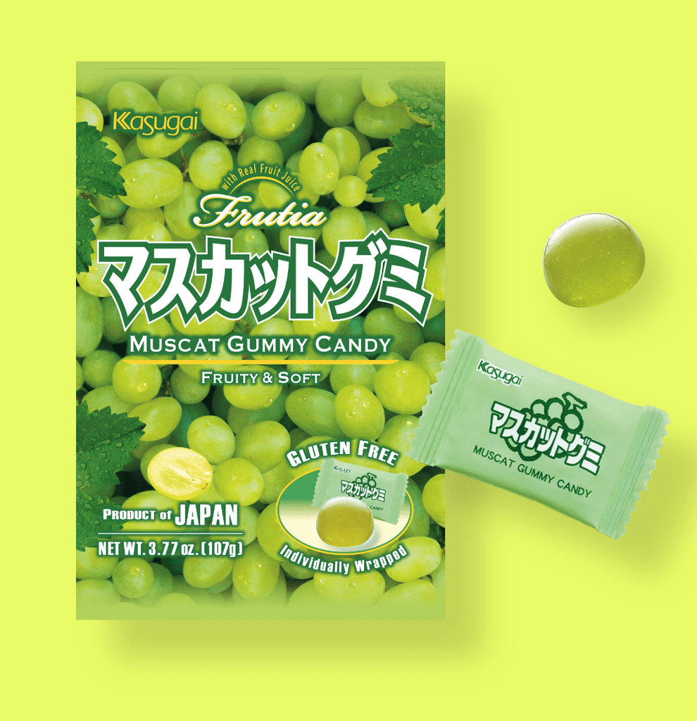 Top-down view of a Kasugai Japanese Muscat Gummy package and a wrapped candy beside an unwrapped green gummy on a pale lime background
