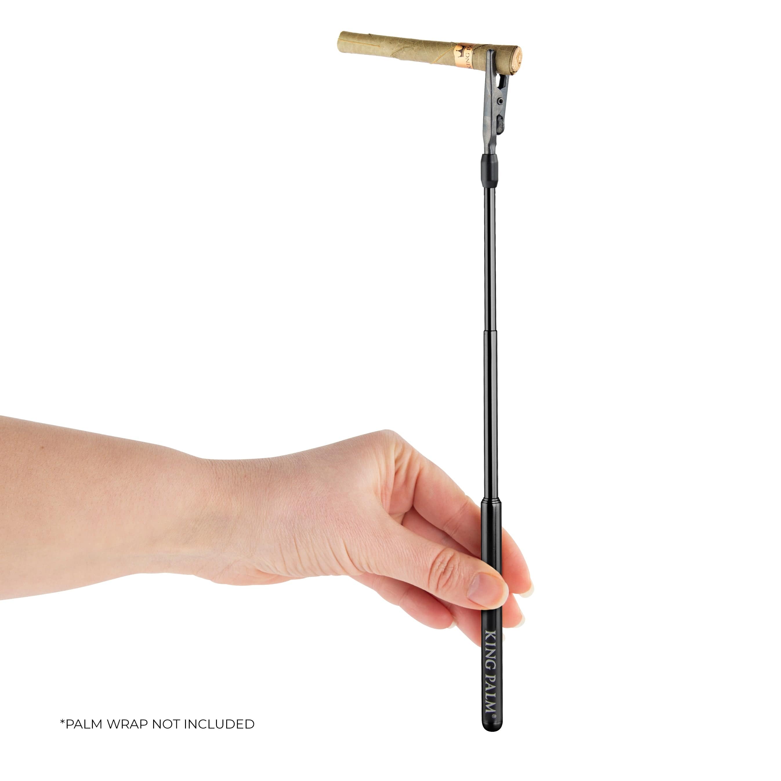 A hand holds the black King Palm Roach Clip against a plain white background, showcasing its sleek, cylindrical shape.