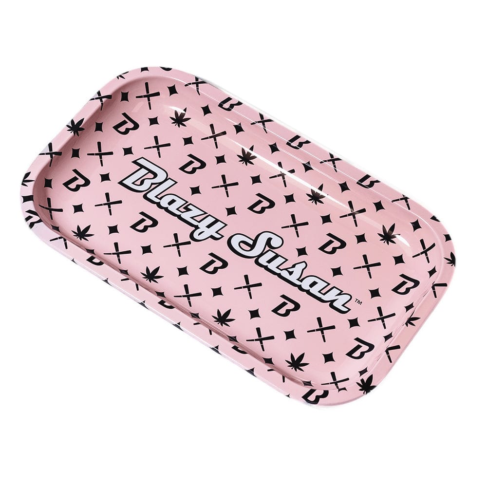 Angled top-down view of a pink Blazy Susan Metal Rolling Tray patterned with black leaf, "B" and cross motifs and the Blazy Susan logo across the center