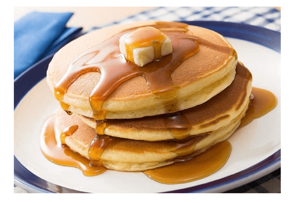 A stack of fluffy pancakes made with Fluffy Hot Pancake Mix, drizzled with syrup, presented on a blue patterned plate.