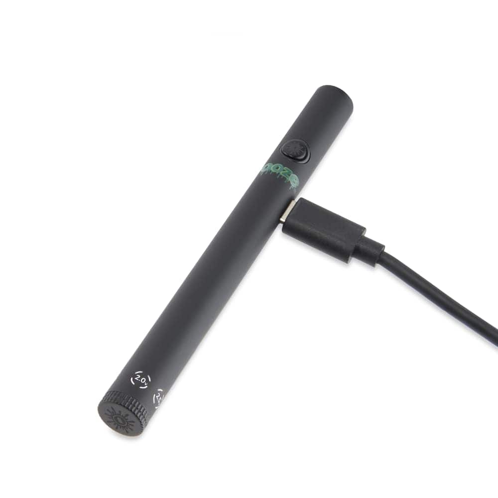 A slightly angled view of the Twist Slim Pen 2.0 510 Thread Vaporizer Battery with a black finish and a USB charging cable attached.