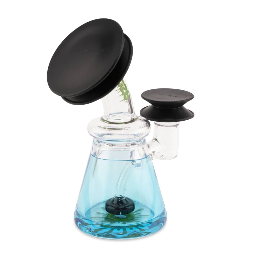 Angled front view of a small glass rig topped with two black Ooze Resolution Caps, the blue-tinted beaker base and clear neck shown against a white background.